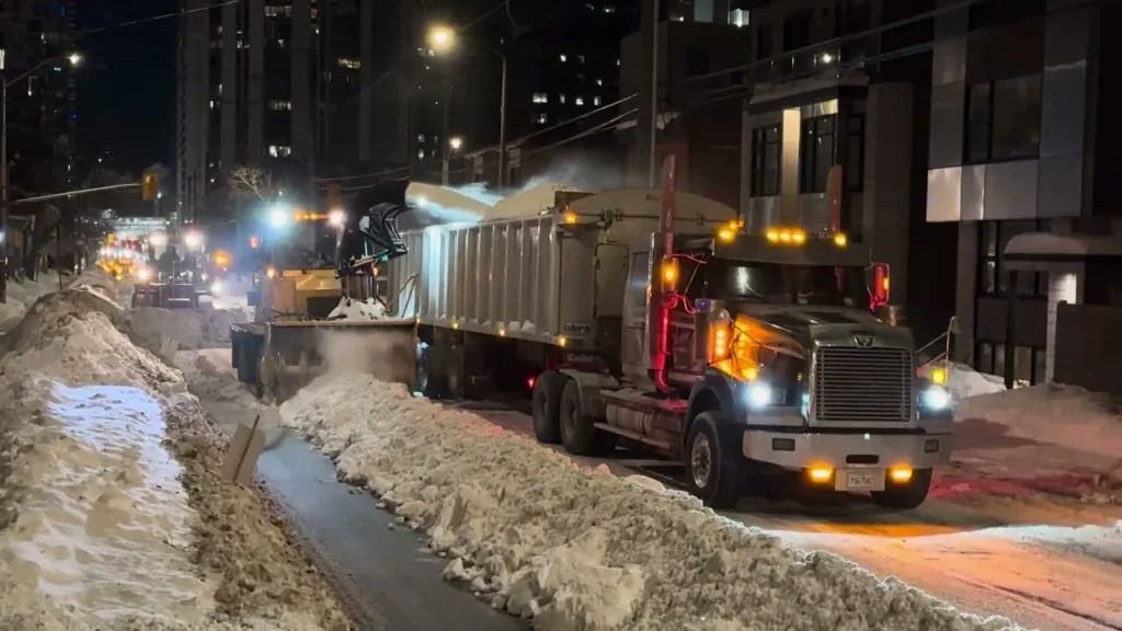 Industrial snow blower loading snow into a dump truck during overnight commercial snow hauling in Green Bay