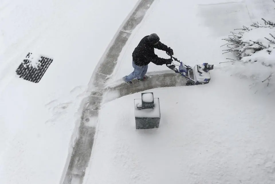 Snow being cleared from a home sidewalk with a professional snow blower in Brown County after a significant winter storm.