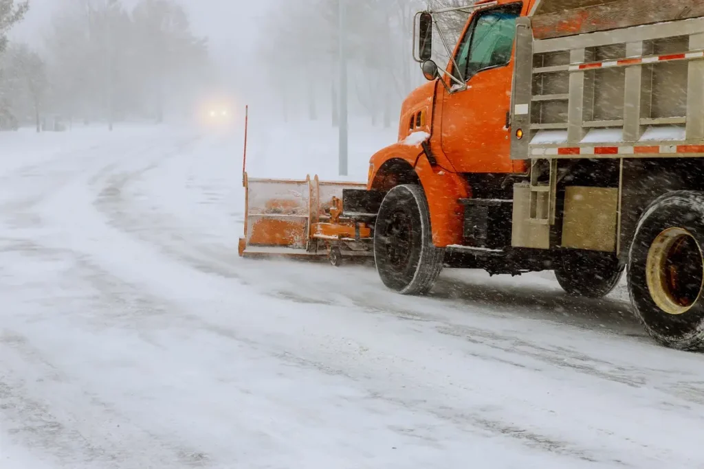 Close-up of an orange heavy wheel loader bucket pushing deep snow during commercial snow removal in Green Bay
