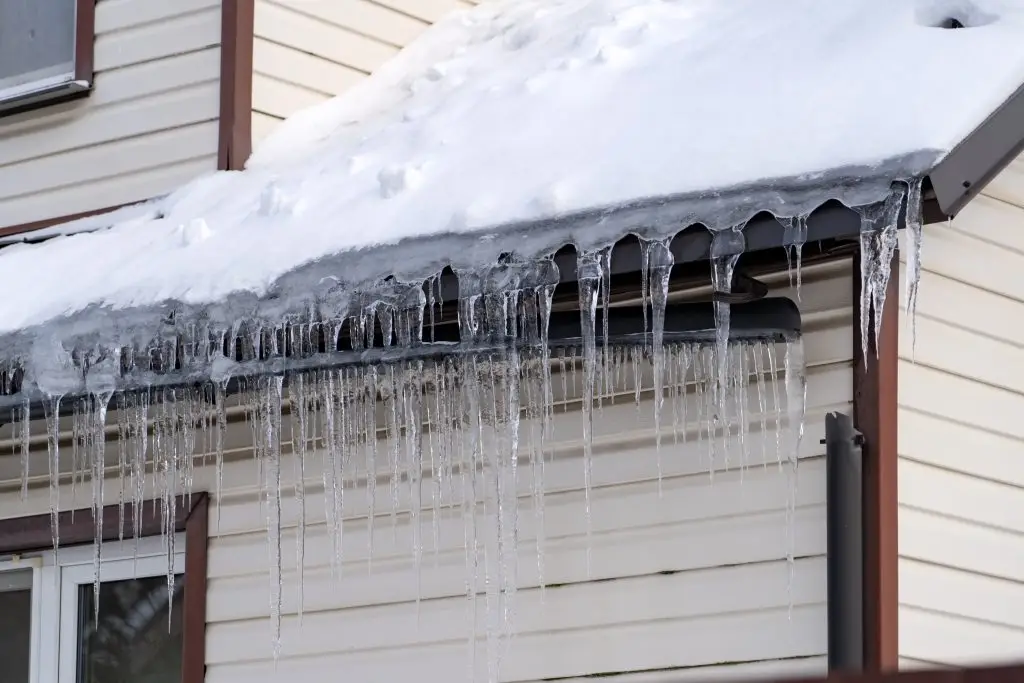 Large icicles hanging from gutters showing severe roof ice dam buildup in Green Bay WI