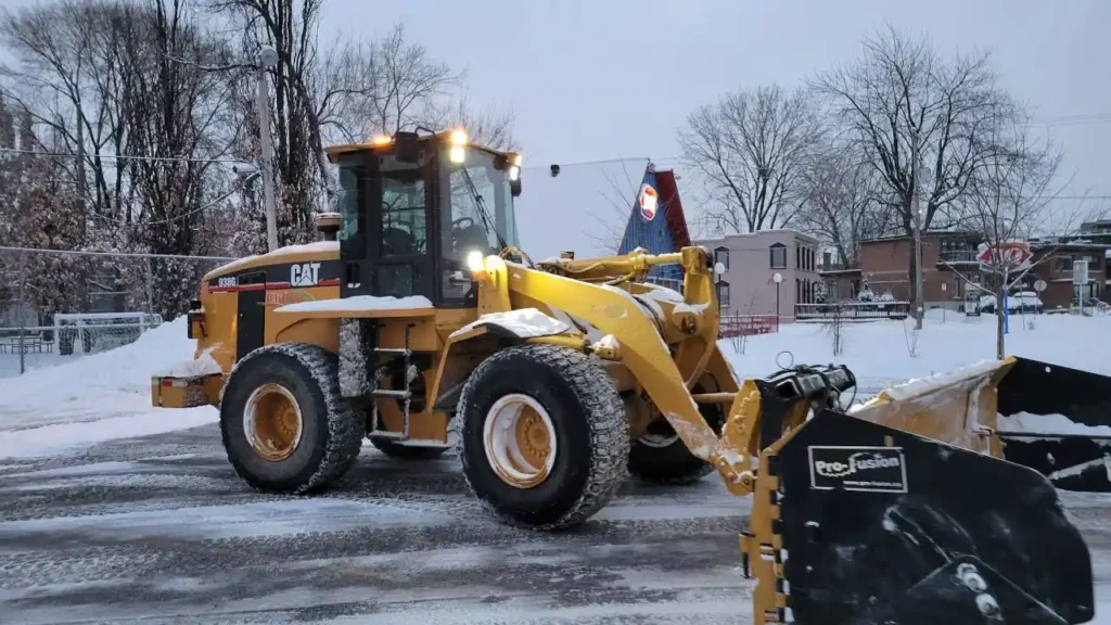 Heavy CAT wheel loader equipped with a snow plow clearing commercial property in Green Bay WI