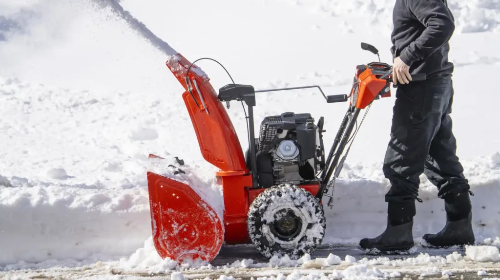 Operator using an orange snow blower machine for efficient snow plowing in Green Bay